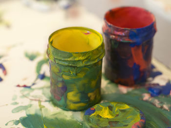 Close-up of messy paint containers on table