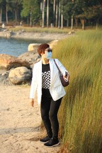 Full length of woman wearing face mask standing by plants