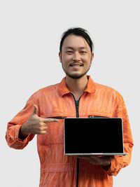 Portrait of man holding smart phone while standing against white background