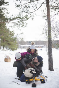 Cheerful girls playing with father on snow during vacation