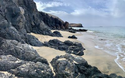 Rock formation on beach against sky