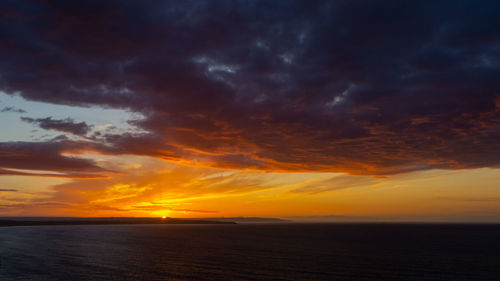 Scenic view of sea against dramatic sky during sunset