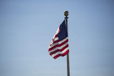 Low angle view of american flag waving against clear blue sky