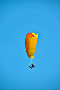 Low angle view of hot air balloons against clear blue sky