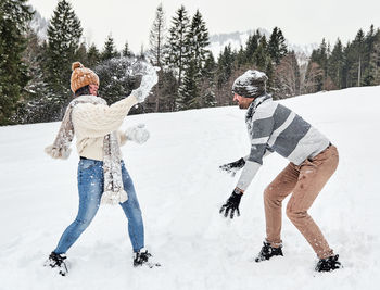 Young couple in winter sweaters having a snowball fight outdoors. snow, happy, fun.