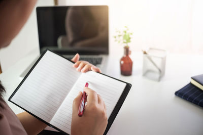 Midsection of woman reading book at table