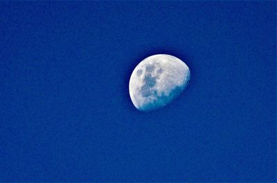 Low angle view of moon in blue sky