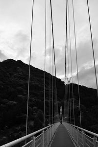 Footbridge over mountain against sky