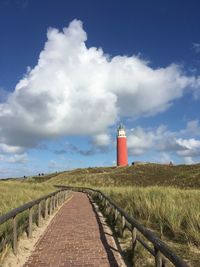 Lighthouse on field against sky