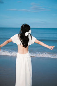 Rear view of woman standing against sea