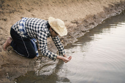 Full length of man drinking water from pond