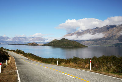 Road by lake against blue sky