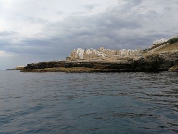 Scenic view of sea by buildings against sky