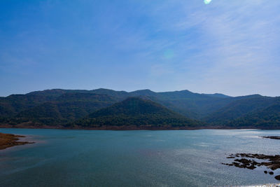 Scenic view of lake and mountains against blue sky