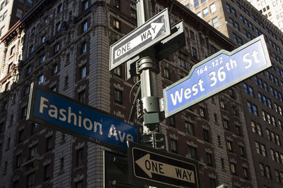 Low angle view of street signs against buildings new york city.