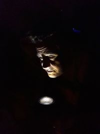 Man with illuminated flashlight looking away in darkroom