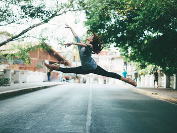 Woman jumping on road in city