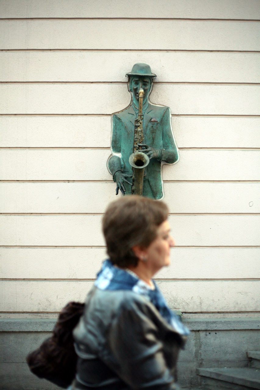 MAN STANDING AGAINST WALL AND SHUTTER