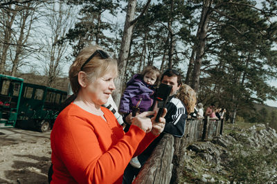 An elderly woman takes photographs of a nature reserve with her smartphone.