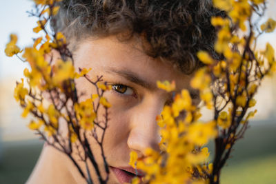 Close-up portrait of young woman with yellow flower