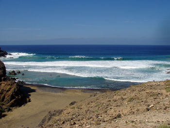 Scenic view of beach against clear blue sky