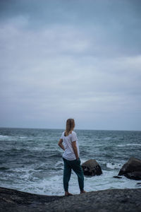 Rear view of woman on beach against sky