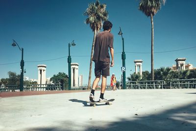 Rear view of man skateboarding on skateboard against sky