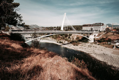 Bridge over river in city against sky