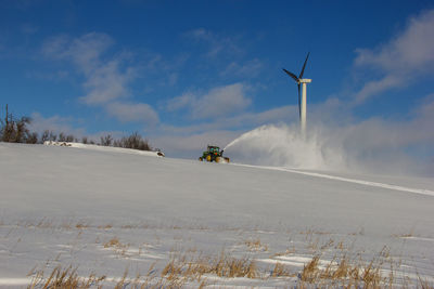 Windmills on snow field against sky