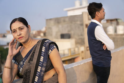 Young man looking away while standing against built structure