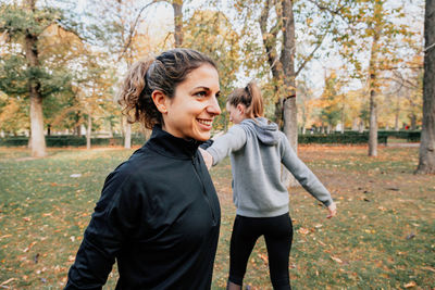 Friends exercising in park amidst trees during autumn