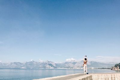Woman looking at sea against blue sky