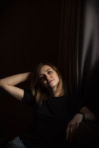 Portrait of woman sitting against black background