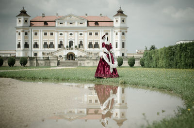 Woman walking towards palace against sky