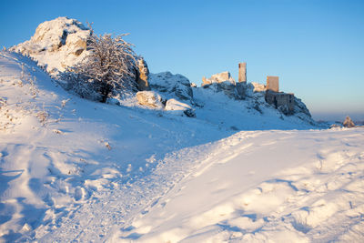 Snow covered field against clear blue sky