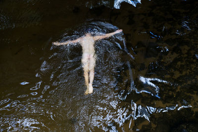 High angle view of naked man swimming in pond