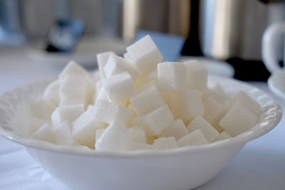 Close-up of white sugar cubes in bowl on table. 