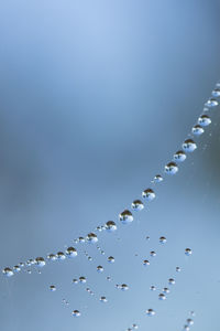 Low angle view of water drops against clear blue sky