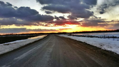 Snow covered road passing through field