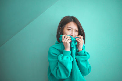 Portrait of young woman sitting against wall