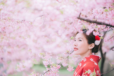 Low angle view of woman with pink cherry blossom