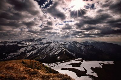 Snowcapped mountains against cloudy sky