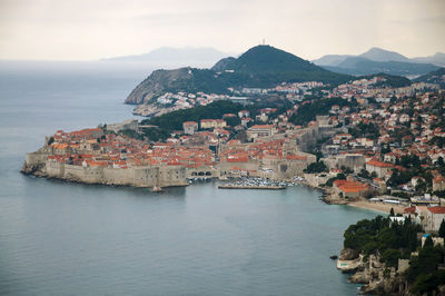 Aerial view of town by sea against sky