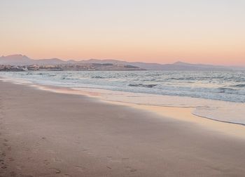 Scenic view of beach against clear sky during sunset