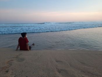 Man on beach against sky during sunset