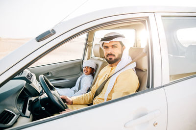 Father and son sitting in car at desert