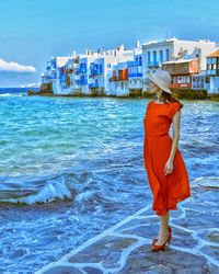 Full length of woman standing by sea against sky in city