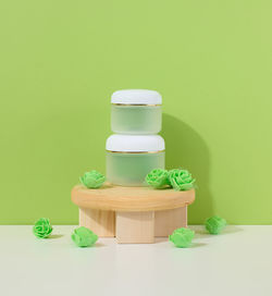 Green jar for cosmetics on a white table. packaging for cream, gel, serum, advertising and 