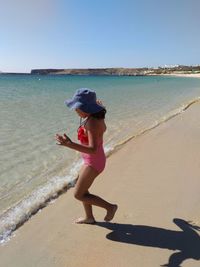 Young woman standing on beach against clear sky