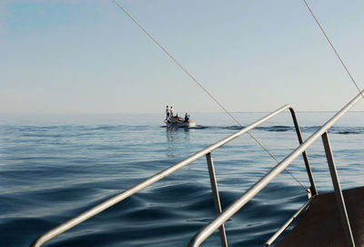 People in boat at sea against clear sky